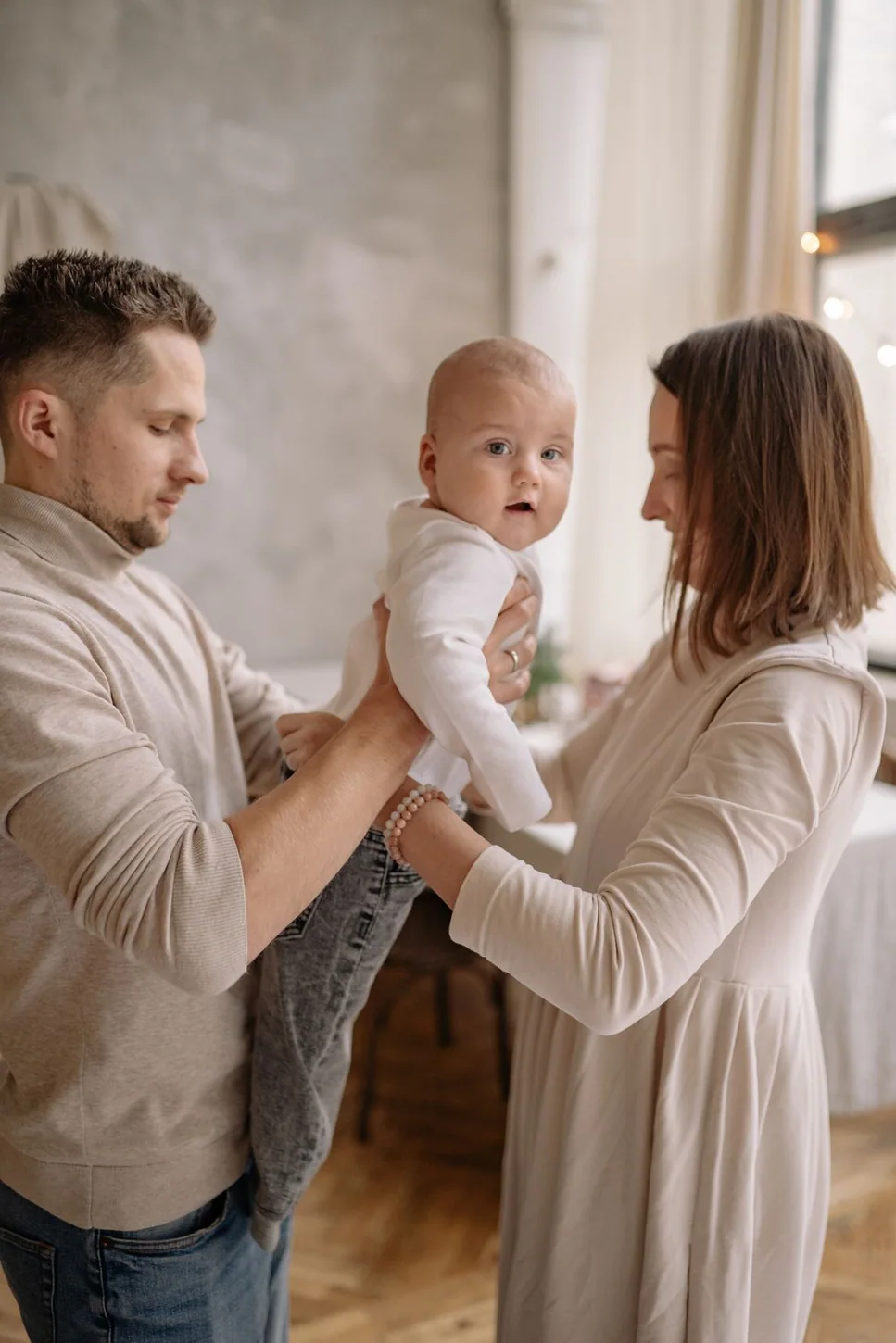 Светлый семейный портрет родителей с малышом в уютном интерьере